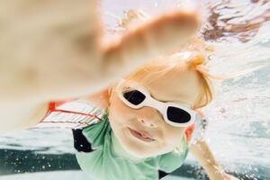 young boy swimming under water in swimming pool scaled