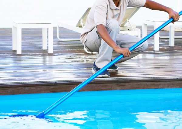Pool cleaner during his work. Hand african hotel staff worker cleaning the pool.
